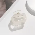 Close-up of a pearlescent square acetate hair claw clip with golden metal spring detail - Pearlescent Creamy White (A)