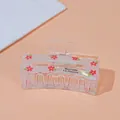 Close-up of translucent acrylic hair claw featuring red floral pattern and brand lettering - Square Flower / Medium
