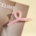 Vue détaillée de la grande pince à cheveux rose nacré avec des détails de ressort doré - Rose