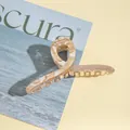 Macro view of a large amber-pattern acrylic hair claw clip with golden glitter details - Off White