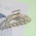 Detailed macro view of pearlescent flower hair claw clip with crystal rhinestones - Green