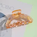 Detailed view of amber resin claw clip with sparkling rhinestones and floral accents - Brown
