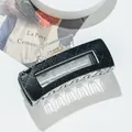 Close-up of black quilted acrylic hair claw clip with glitter finish and gold spring - Black
