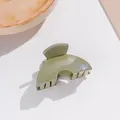 Gros plan d'une petite pince à cheveux verte scintillante avec finition brillante et forme d'éventail - Vert