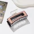 Détail d'une pince à cheveux carrée en acétate rose nude avec ressort en métal doré robuste - Rose + Noir
