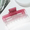 Detail view of large matte pink gradient rectangle hair claw clip on white platform - Red