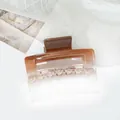 Detail of square acrylic hair claw with brown glitter gradient and hollow design - Coffee