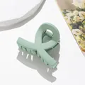Primer plano de una pinza para el cabello verde mate sobre un fondo blanco minimalista - Verde