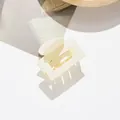 Detail of a cream square matte hair claw clip with a hollow design and sturdy metal spring - Beige