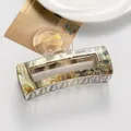 Macro detail of large marble-patterned hair claw clip with artistic calligraphy design - Yellow