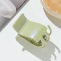Detailed view of avocado green glitter shark hair claw clip on a stylish amber tray - Green