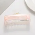 Makroaufnahme einer großen Haarklammer aus rosa Acetat mit Barrette La France Schriftzug - Orange