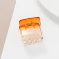 Close-up of square orange gradient hair claw clip with golden metal spring and clear teeth - Gradient Amber Orange (Orange) / Orange