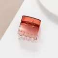 Close-up of square transparent amber hair claw clip with visible metal spring detail - Gradient Amber Red (Red) / Red