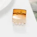 Detail view of a translucent amber gradient square hair claw clip with a strong metal spring - Gold
