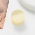 Macro di una pinza per capelli opaca giallo crema con design rotondo e denti interni - Bianco Sporco