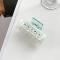 Détail d'une pince à cheveux vert transparent avec fleurs blanches et strass brillants - Bleu