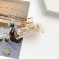 Makro-Detail einer bernsteinfarbenen Haarklammer aus Acryl mit Muschelblüten und Strass - Braun