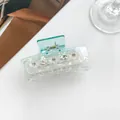 Macro detail of transparent light blue hair claw clip with rhinestones and white floral accents - Sky Blue