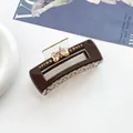 Gros plan d'une pince à cheveux marron foncé ornée de strass en forme de cœur et d'un fini brillant - café