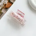 Macro detail of pink translucent hair claw clip with crystal-studded floral decorations - Pink