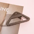 Detail van een matbruine driehoekige haarklem met een geometrisch hol ontwerp - koffiekleur