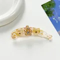 Detalle macro de la pinza de pelo banana ámbar con flores de cristal y motivos de mariposa - Amarillo
