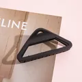 Detail van matte zwarte holle driehoekige haarklem op roze tijdschrift achtergrond - Zwart