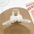 Detalle de pinza para el pelo transparente con lazo, perla y resorte dorado fuerte - Blanco