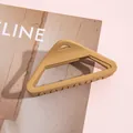 Detail van een matte mosterdgele geometrische driehoekige haarklem op roze - Khaki