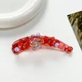 Détail d'une pince à cheveux banane rouge avec fleurs en cristal et perles sur blanc - Rouge