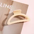 Dettaglio di una pinza per capelli color crema opaco con design curvo su rivista di moda - Bianco Sporco
