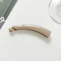Nahaufnahme einer kleinen, glänzenden, hellbraunen Bananen-Haarklammer auf weißem Tisch - Hellbeige