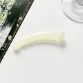 Close-up of a translucent cream yellow banana hair clip on a clean white background - White