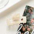 Vista macro de una pinza de pelo rectangular de acetato jaspeado crema con resorte fuerte - Blanco Roto