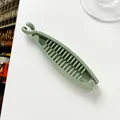 Detail view of the inner teeth and locking clip of a matte green banana hair clip - Green