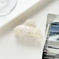 Dettaglio della molletta per capelli in acetato crema con trama marmorea su sfondo sobrio - Bianco Sporco
