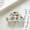 Detail view of acetate hair claw clip with grey and white marble pattern on white desk - Gray