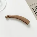 Macro shot of glossy brown banana hair clip with internal teeth on minimalist background - Dark Khaki