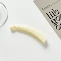 Glänzende cremefarbene Bananenspange für Haare auf minimalistischem Kartenhintergrund - Gebrochenes Weiß