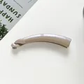 Detalle de la pinza de pelo tipo banana color champán perlado en superficie mínima - Caqui
