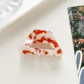Detailed view of red and white marbled acetate hair claw on a decorative tray - Marble Texture Trapezoid Style / Red