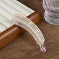 Detail of a pearlescent cream banana hair clip with France text in a wooden box - Off White