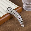 Detalle de la pinza de banana blanca con letras France sobre soporte de madera - Negro