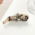 Close-up of banana hair clip with tortoiseshell texture and sparkling flower details - Coffee