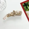 Detailed macro view of a resin banana clip with marble texture and glittery floral design - Off White