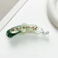 Gros plan détaillé sur un clip banane vert clair orné de fleurs en strass étincelants - Vert