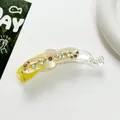 Détail de pince à cheveux banane avec strass et fleur translucide sur fond blanc pur - Jaune
