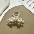 Detail von perlmuttfarbenem Herz-Haarclip mit Strasssteinen und goldener Metallfeder - Weiß