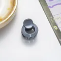 Detail of mini round hair claw clip with glitter finish next to a coffee cup - Gray